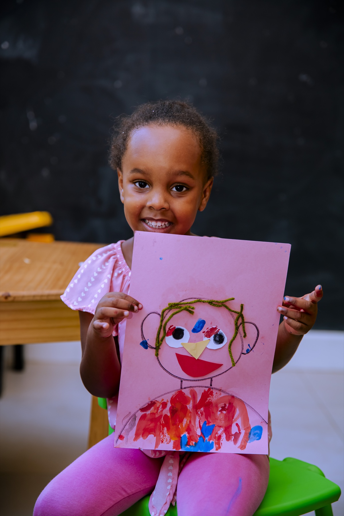 A smiling Evermont learner proudly showing her artwork